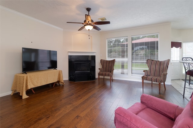 living room featuring ceiling fan, a textured ceiling, ornamental molding, and hardwood / wood-style floors