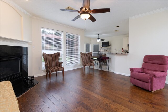 living area featuring ceiling fan, ornamental molding, baseboards, and hardwood / wood-style floors