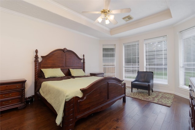 bedroom with crown molding, a raised ceiling, dark wood finished floors, and visible vents