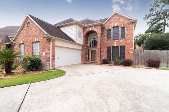 traditional-style home featuring concrete driveway, brick siding, an attached garage, and fence