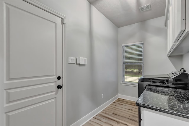 washroom featuring washer and dryer, light hardwood / wood-style flooring, and cabinets