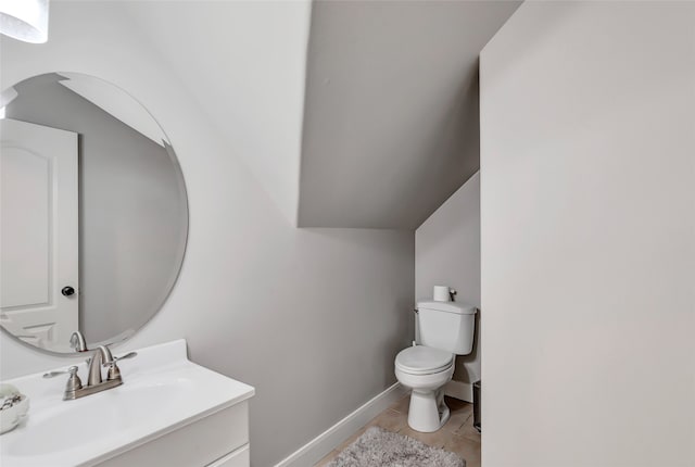 bathroom featuring tile patterned flooring, vanity, lofted ceiling, and toilet