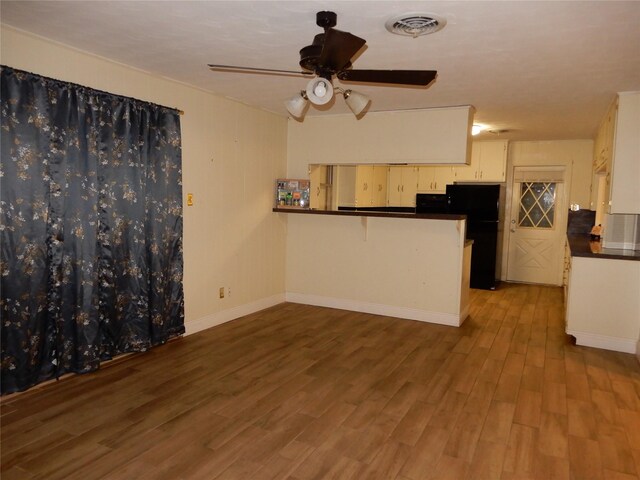 kitchen with ceiling fan, kitchen peninsula, wood-type flooring, and black fridge