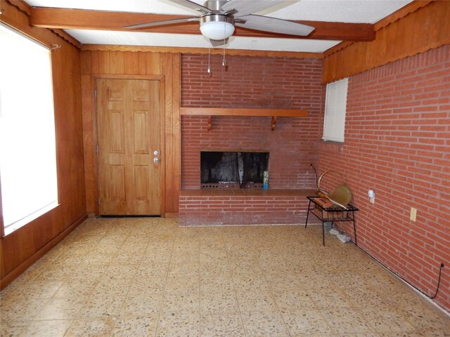 unfurnished living room with a fireplace, light tile patterned floors, ceiling fan, wood walls, and brick wall