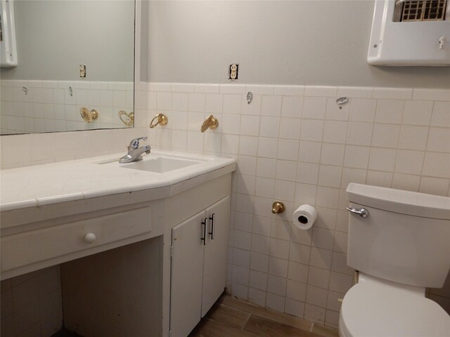 bathroom with tile walls, toilet, and vanity