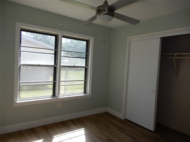 unfurnished bedroom featuring dark hardwood / wood-style floors, ceiling fan, and multiple windows