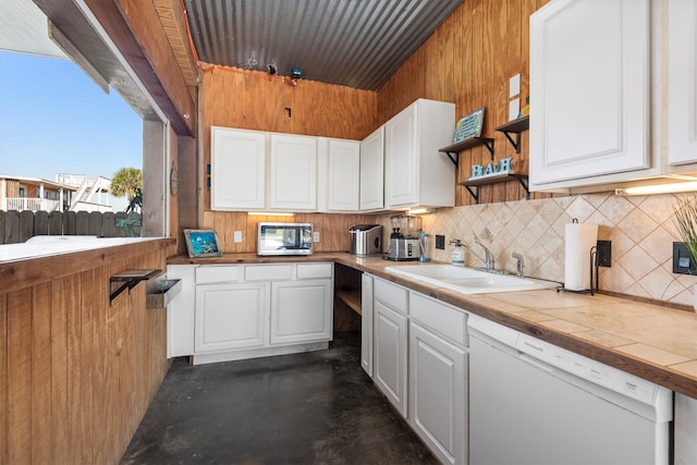 kitchen featuring white cabinets, dishwasher, tile countertops, stainless steel microwave, and a sink