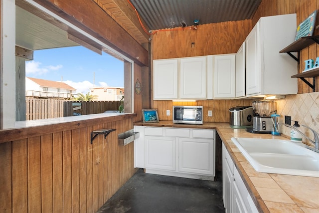 kitchen with a sink, white cabinets, tile counters, decorative backsplash, and stainless steel microwave