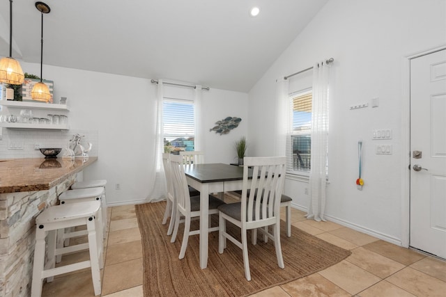 dining room featuring lofted ceiling, light tile patterned flooring, and baseboards