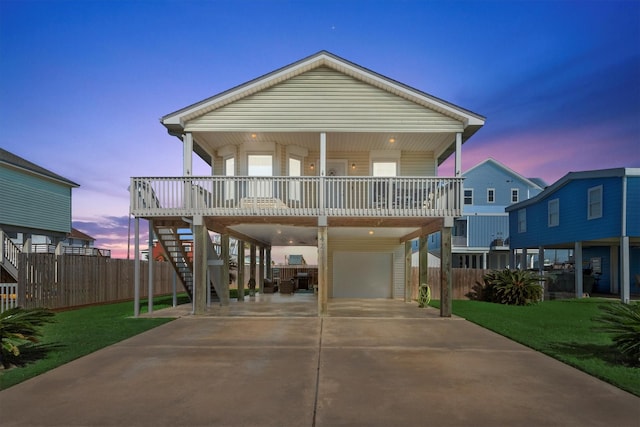 beach home with a porch, a garage, stairs, a lawn, and a carport