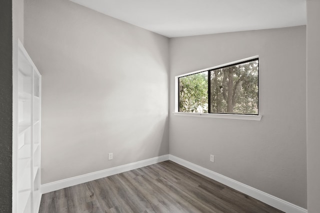 spare room featuring vaulted ceiling and hardwood / wood-style flooring