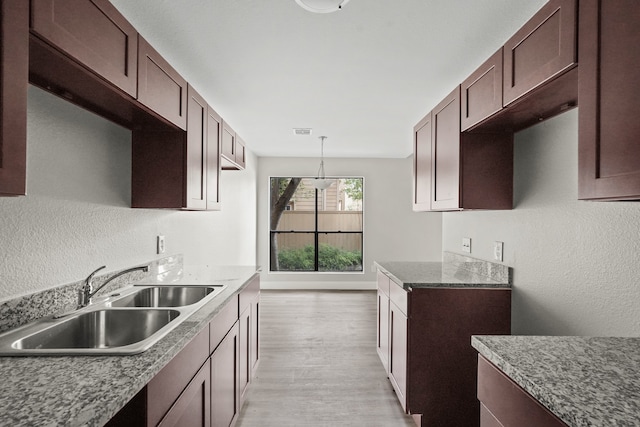 kitchen featuring sink, light hardwood / wood-style flooring, pendant lighting, and dark brown cabinets