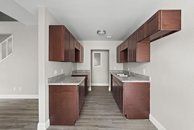 kitchen featuring light wood-type flooring, sink, dark brown cabinetry, and light stone counters