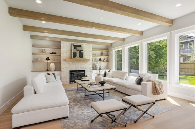 living room with beam ceiling, light wood-type flooring, a fireplace, and built in features