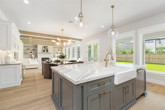 kitchen featuring sink, a center island with sink, beamed ceiling, gray cabinets, and white cabinetry