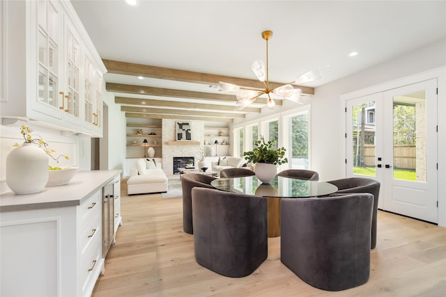 dining room featuring a fireplace, a wealth of natural light, french doors, and beamed ceiling