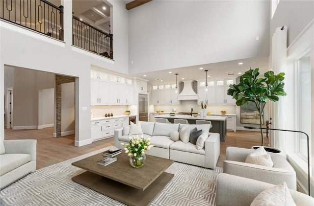 living room with light hardwood / wood-style floors, sink, and a high ceiling