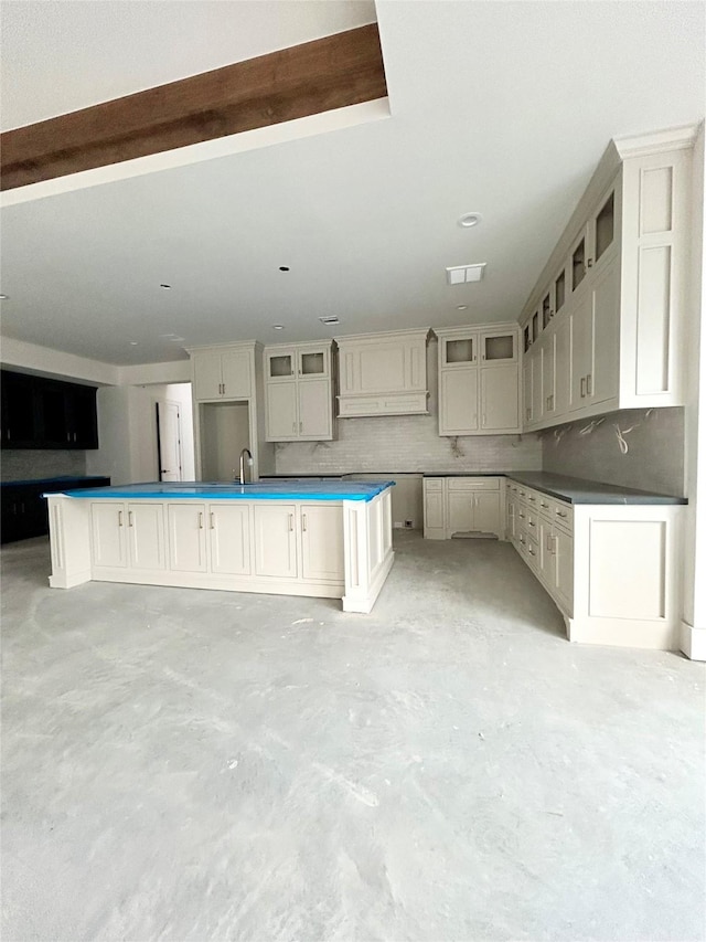 kitchen with sink, backsplash, and an island with sink