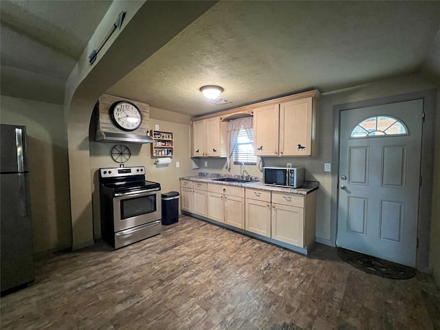 kitchen with appliances with stainless steel finishes, a textured ceiling, hardwood / wood-style flooring, and sink