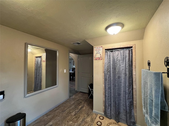 bathroom featuring wood-type flooring and a textured ceiling