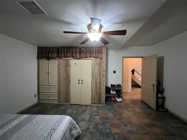 tiled bedroom featuring ceiling fan and a textured ceiling