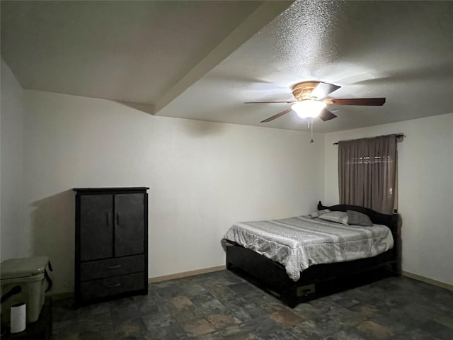 bedroom featuring ceiling fan, dark tile patterned flooring, and a textured ceiling