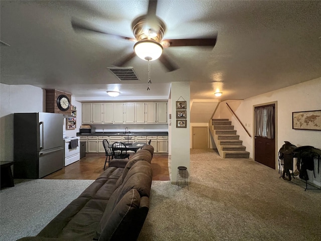 recreation room with ceiling fan, sink, dark carpet, and a textured ceiling