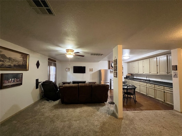 carpeted living room featuring ceiling fan, a textured ceiling, and sink