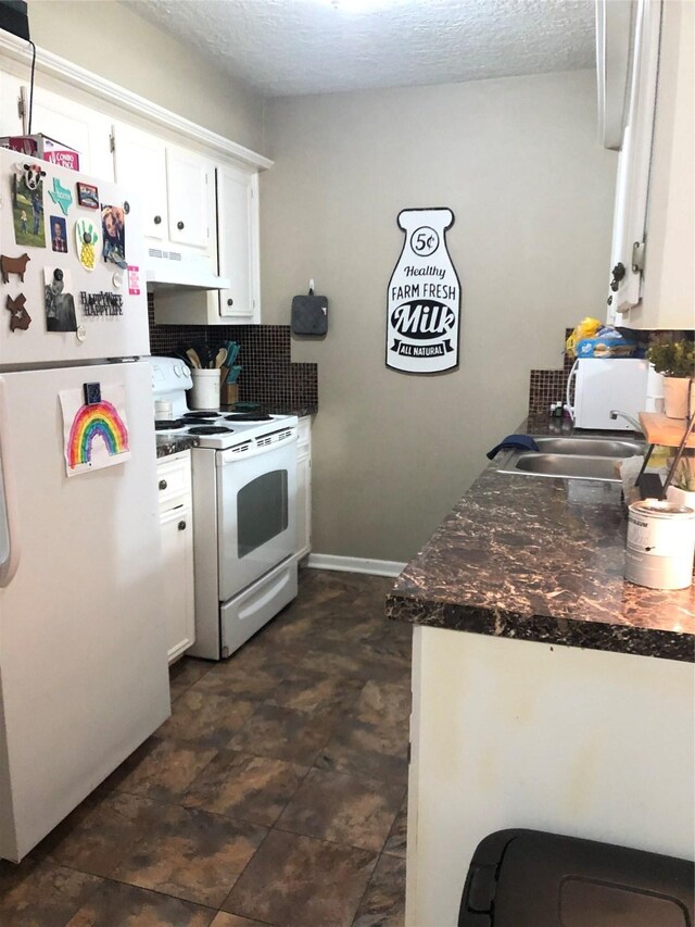 kitchen with white appliances, dark tile patterned floors, a textured ceiling, exhaust hood, and white cabinetry