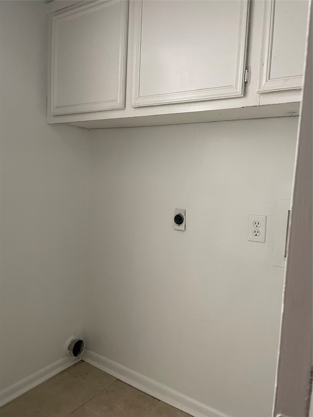 clothes washing area with electric dryer hookup, tile patterned flooring, and cabinets