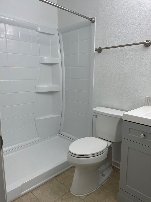 bathroom featuring tile patterned floors, toilet, walk in shower, and vanity