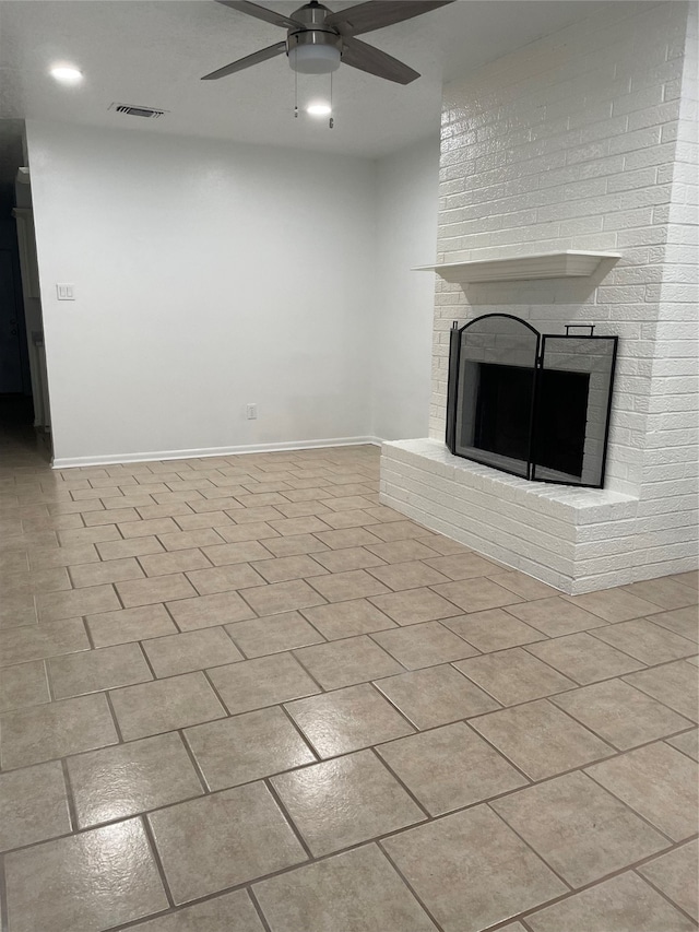 unfurnished living room featuring a fireplace, brick wall, ceiling fan, and light tile patterned floors