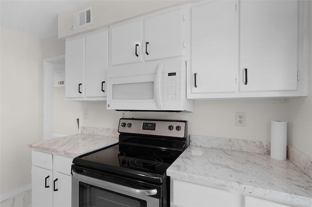 kitchen featuring light stone counters, white microwave, electric range, visible vents, and white cabinets