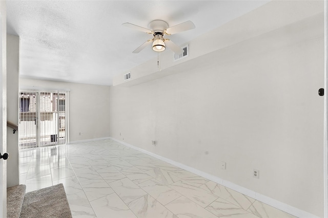 spare room with marble finish floor, baseboards, visible vents, and ceiling fan