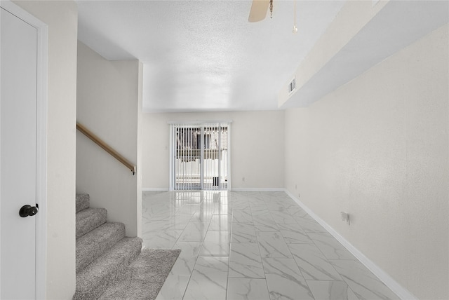 unfurnished living room featuring visible vents, baseboards, stairway, marble finish floor, and a textured ceiling