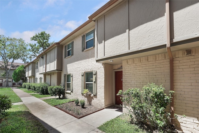 exterior space with a residential view, brick siding, and stucco siding