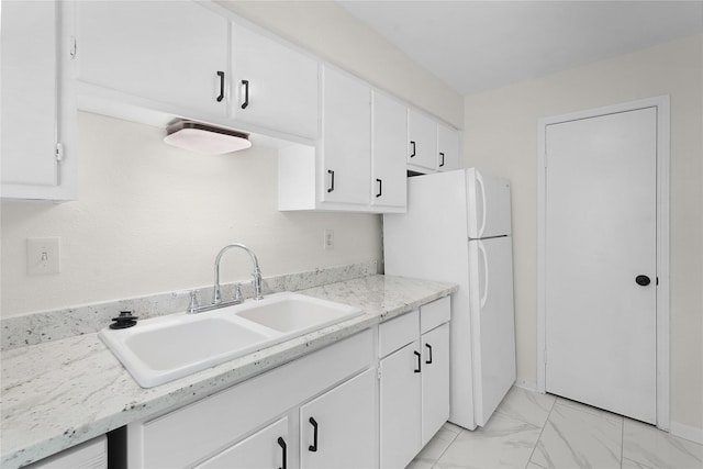 kitchen with freestanding refrigerator, marble finish floor, light countertops, white cabinetry, and a sink