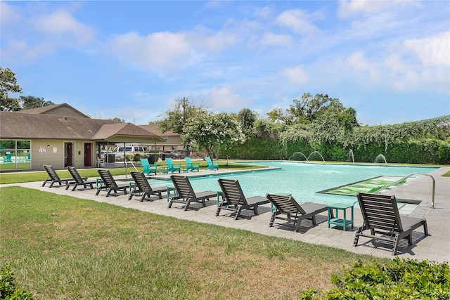 view of swimming pool with pool water feature, a patio area, and a yard