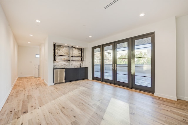 unfurnished living room featuring french doors and light hardwood / wood-style floors