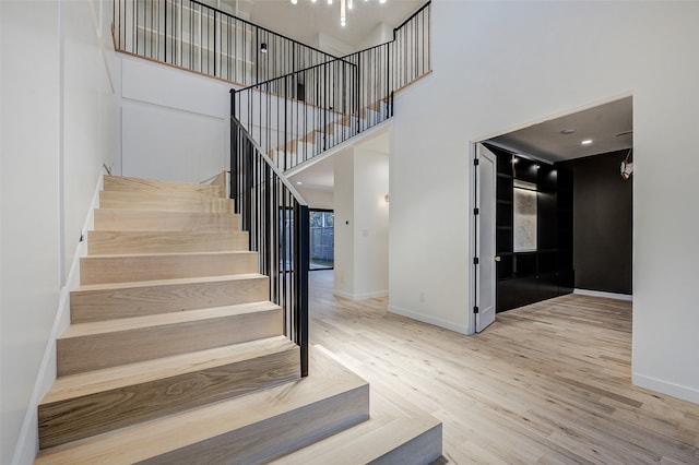 stairway with hardwood / wood-style floors and a towering ceiling