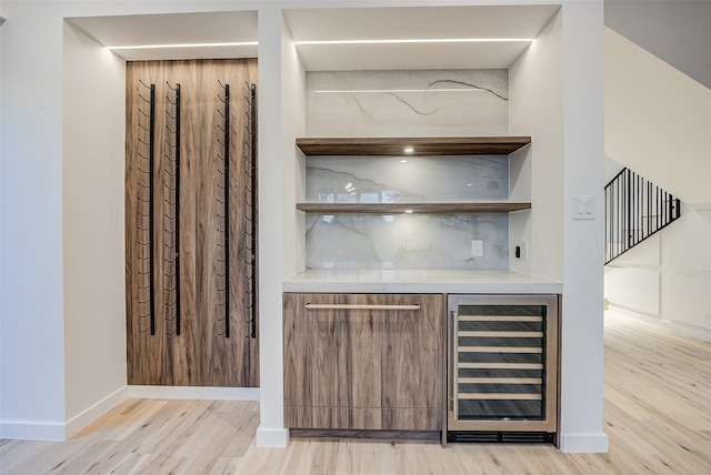 bar featuring light hardwood / wood-style flooring, wine cooler, and tasteful backsplash