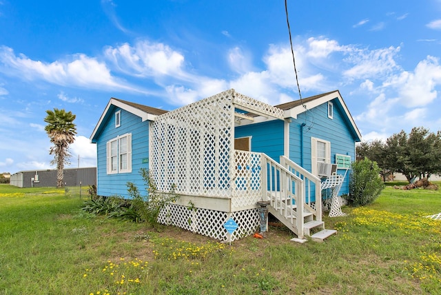 rear view of house with cooling unit and a lawn