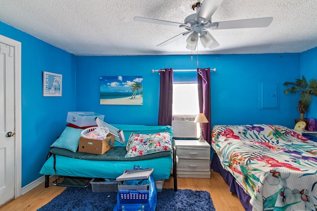 bedroom featuring a textured ceiling, ceiling fan, cooling unit, and light wood-type flooring