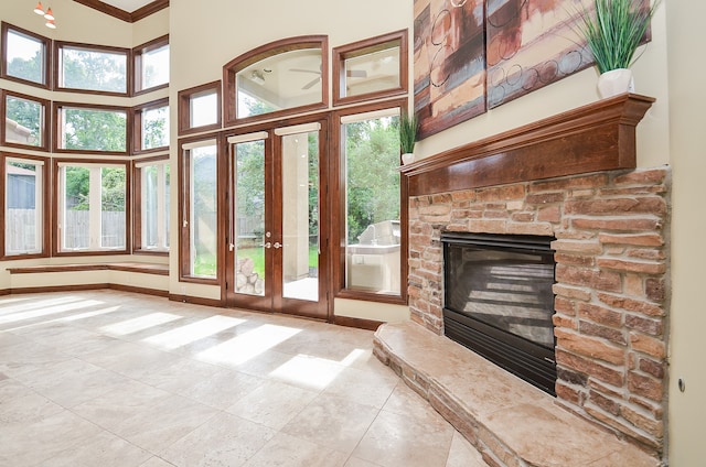 unfurnished living room featuring a fireplace, plenty of natural light, light tile patterned flooring, and a towering ceiling