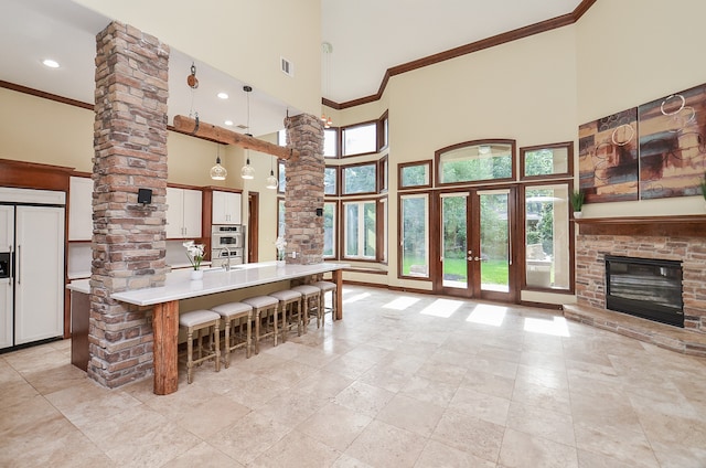 kitchen featuring white cabinetry, a high ceiling, crown molding, pendant lighting, and a breakfast bar area