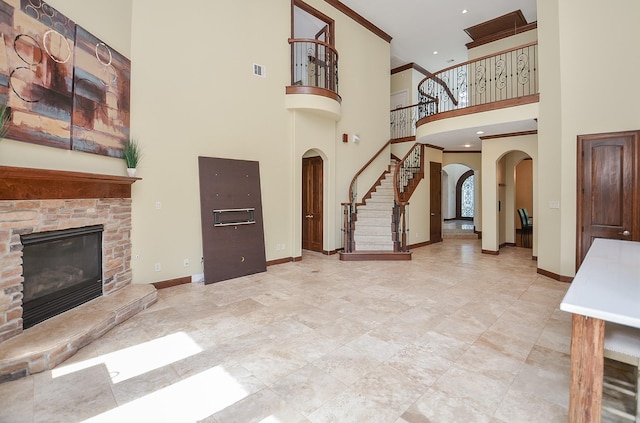 living area with visible vents, arched walkways, baseboards, and a stone fireplace