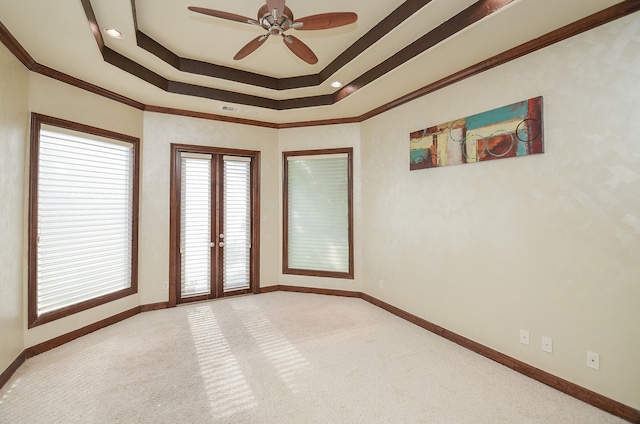 carpeted empty room with ceiling fan, a raised ceiling, and crown molding