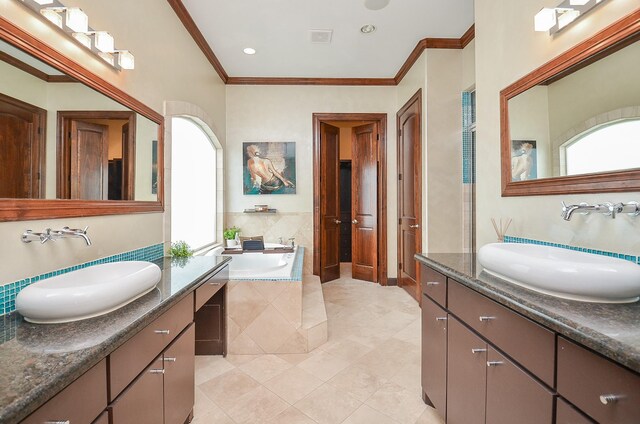 bathroom featuring tiled tub, tile patterned flooring, double vanity, and crown molding