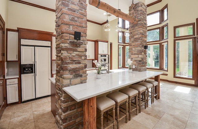 kitchen with light tile patterned flooring, paneled built in refrigerator, pendant lighting, and a high ceiling