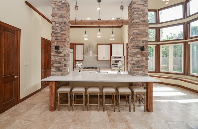 kitchen featuring wall chimney range hood, plenty of natural light, pendant lighting, and a high ceiling